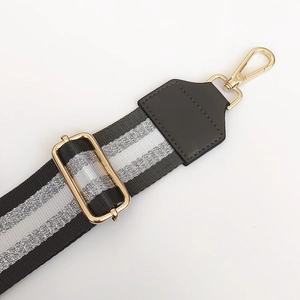 Close-up of adjustable nylon bag strap with silver wire stripes and gold metal hardware