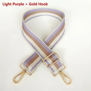 Close-up of adjustable striped bag strap with gold metal lobster hooks and slider
