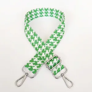 Detail view of houndstooth bag strap in green and white with silver metal swivel hooks
