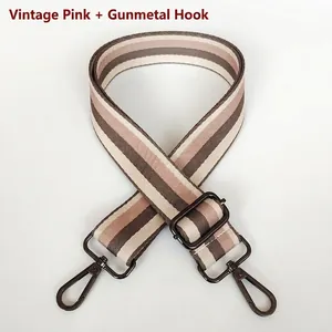 Detail of adjustable woven bag strap with pink and brown stripes and metal hooks
