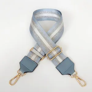 Detail of light lake blue and silver woven nylon bag strap with gold metal hardware
