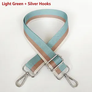 Detailed view of striped canvas strap in light green and brown with silver metal hooks