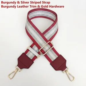 Close-up of wine red nylon bag strap with silver stripes and gold metal hardware