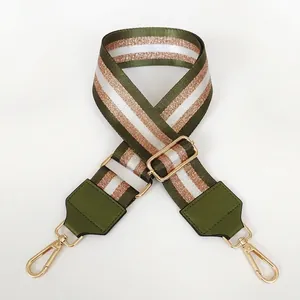 Detail of army green nylon bag strap with gold metal hooks and adjustable buckle