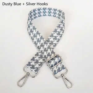 Detail of foggy blue houndstooth wide bag strap with silver metal hooks and buckle