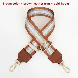 Detail view of brown nylon webbing strap with silver stripes and gold metal hooks