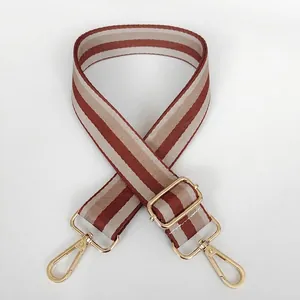 Close-up of brown striped adjustable fabric bag strap with golden metal swivel hooks