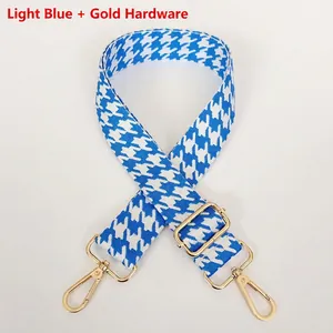 Detail of light blue houndstooth woven shoulder strap with gold metal hooks and buckle