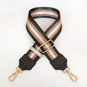 Detail of adjustable wide 5cm nylon bag strap with dark grey stripes and gold metal hooks