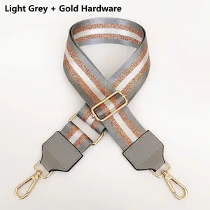 Detail of light grey nylon bag strap with gold lobster clasps and rose gold silk stripes
