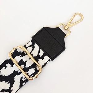 Close-up of black and white geometric pattern bag strap with gold metal lobster clasp