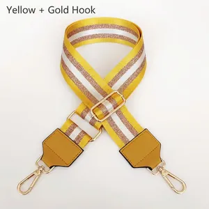 Detail of adjustable yellow and white striped nylon bag strap with gold metal buckles