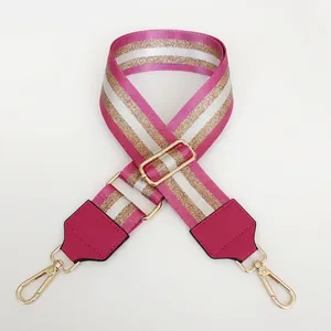 Detail of adjustable rose red striped nylon bag strap with gold metal lobster clasps