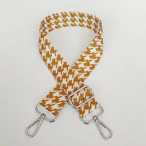 Detail view of houndstooth jacquard bag strap in yellow brown with silver metal hooks