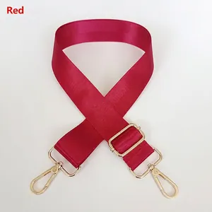 Detail view of burgundy nylon shoulder strap with golden metal buckles and spring hooks