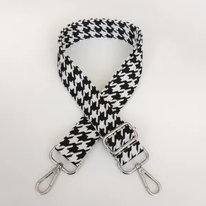 Close-up of houndstooth jacquard strap with silver metal swivel hooks and adjuster