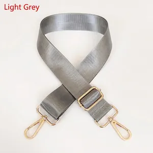 Detail view of light grey nylon shoulder strap with gold-tone lobster clasps and buckle