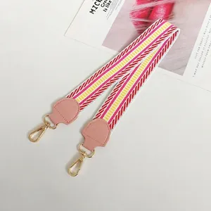 Close-up of pink ethnic woven canvas bag strap with golden metal snap hooks