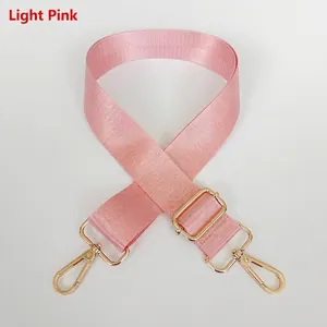Detail of light pink wide nylon bag strap with gold metal buckle and adjustable clasp