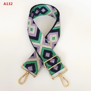 Detail of colorful geometric diamond jacquard bag strap with gold metal hooks and buckle