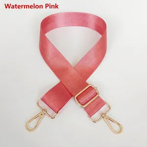 Detail view of watermelon pink nylon bag strap with gold metal buckle and hooks