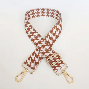Close-up of houndstooth woven handbag strap with light brown pattern and gold metal hooks
