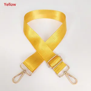 Detail of adjustable yellow nylon bag strap with high-density weave and gold metal hooks