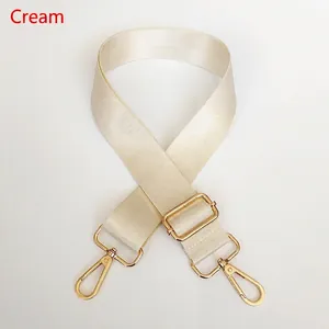 Detail view of the beige nylon bag strap with shiny gold rotating metal hooks