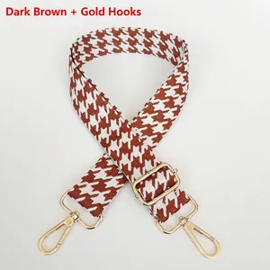 Detail of dark brown houndstooth canvas bag strap with golden metal swivel hooks