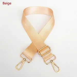 Detail of adjustable beige nylon strap with polished light gold metal swivel hooks