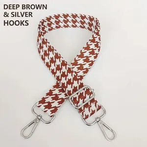 Detail of dark brown houndstooth bag strap with silver metal swivel hooks and buckles