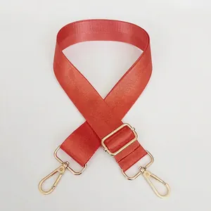 Detail of adjustable orange nylon shoulder strap with golden metal lobster clasps
