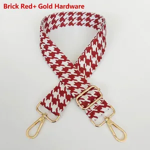 Detail of red houndstooth jacquard wide bag strap with adjustable gold metal hooks