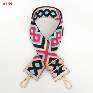 Macro detail of geometric jacquard bag strap with gold adjustable metal buckles