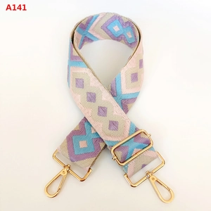 Detail of colorful geometric jacquard bag strap with gold metal lobster clasps and buckles