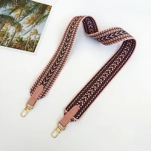 Detail view of 5cm wide pink woven canvas bag strap with geometric arrow pattern and gold hooks