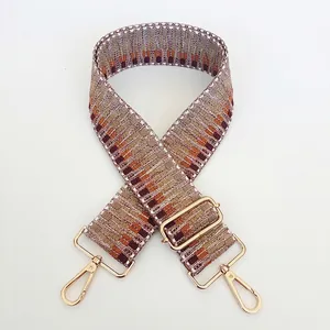 Detail view of woven shoulder strap with geometric embroidery and gold metal clasp