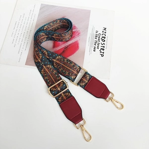 Detail of bohemian woven wide bag strap with red leather ends and gold metal buckles