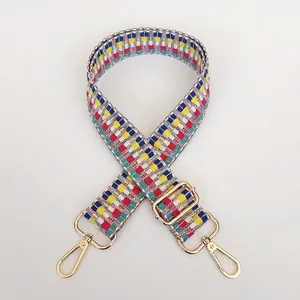 Detail view of colorful checkerboard woven bag strap with adjustable gold hardware buckles