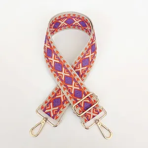 Detail of bohemian geometric purple and orange canvas bag strap with gold metal hooks