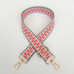 Detail of adjustable woven shoulder strap with pink geometric patterns and gold hooks