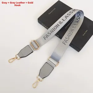 Detail of adjustable gray nylon bag strap with Fashion & Classic text and gold metal hooks