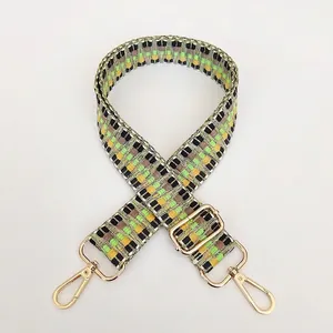 Detail of adjustable geometric woven shoulder strap with gold metal hooks and buckle