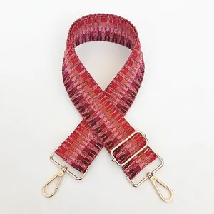 Close-up of ethnic red geometric woven strap with gold metal hooks and buckle
