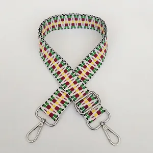 Detail of woven bag strap featuring colorful geometric patterns and silver swivel hooks