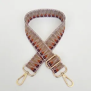 Detail view of woven bag strap with geometric patterns and gold metal swivel snap hooks
