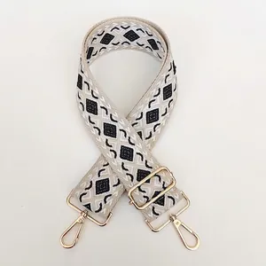 Macro view of geometric jacquard bag strap with polished gold-tone metal clips