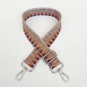 Macro detail of geometric embroidered bag strap with silver metal swivel hooks