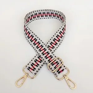 Detail of red and black geometric woven bag strap with golden metal swivel hooks
