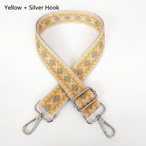 Detail of wide canvas bag strap with yellow geometric pattern and silver hooks